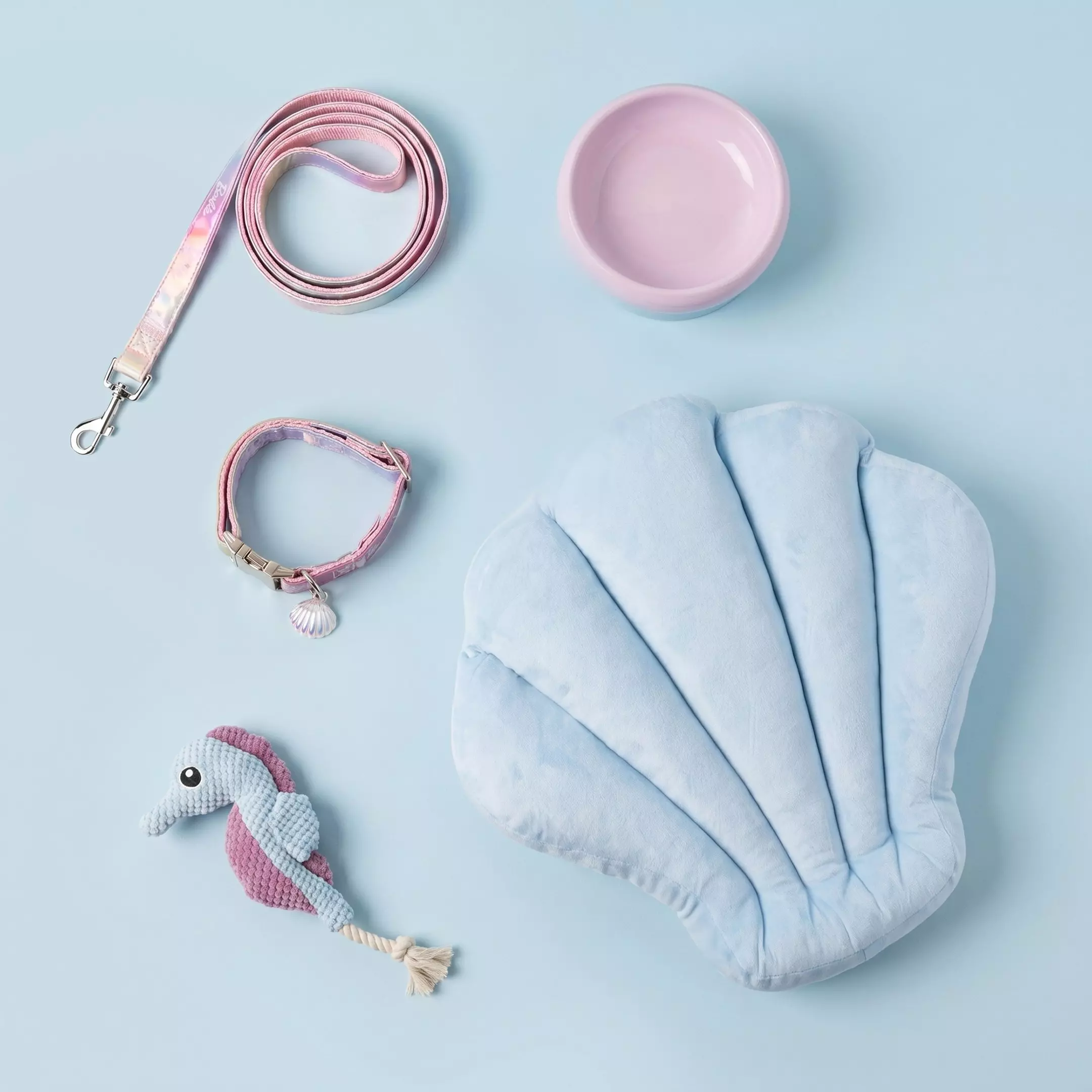 Accesorios Pepco para mascotas: correa rosa, collar con colgante de concha, cuenco rosa, juguete y cama azul.