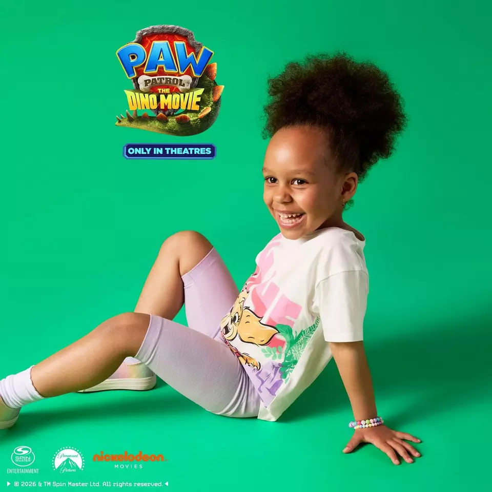 Niña sonriente de Pepco vistiendo conjunto de PAW Patrol The Dino Movie con camiseta y leggings lila.