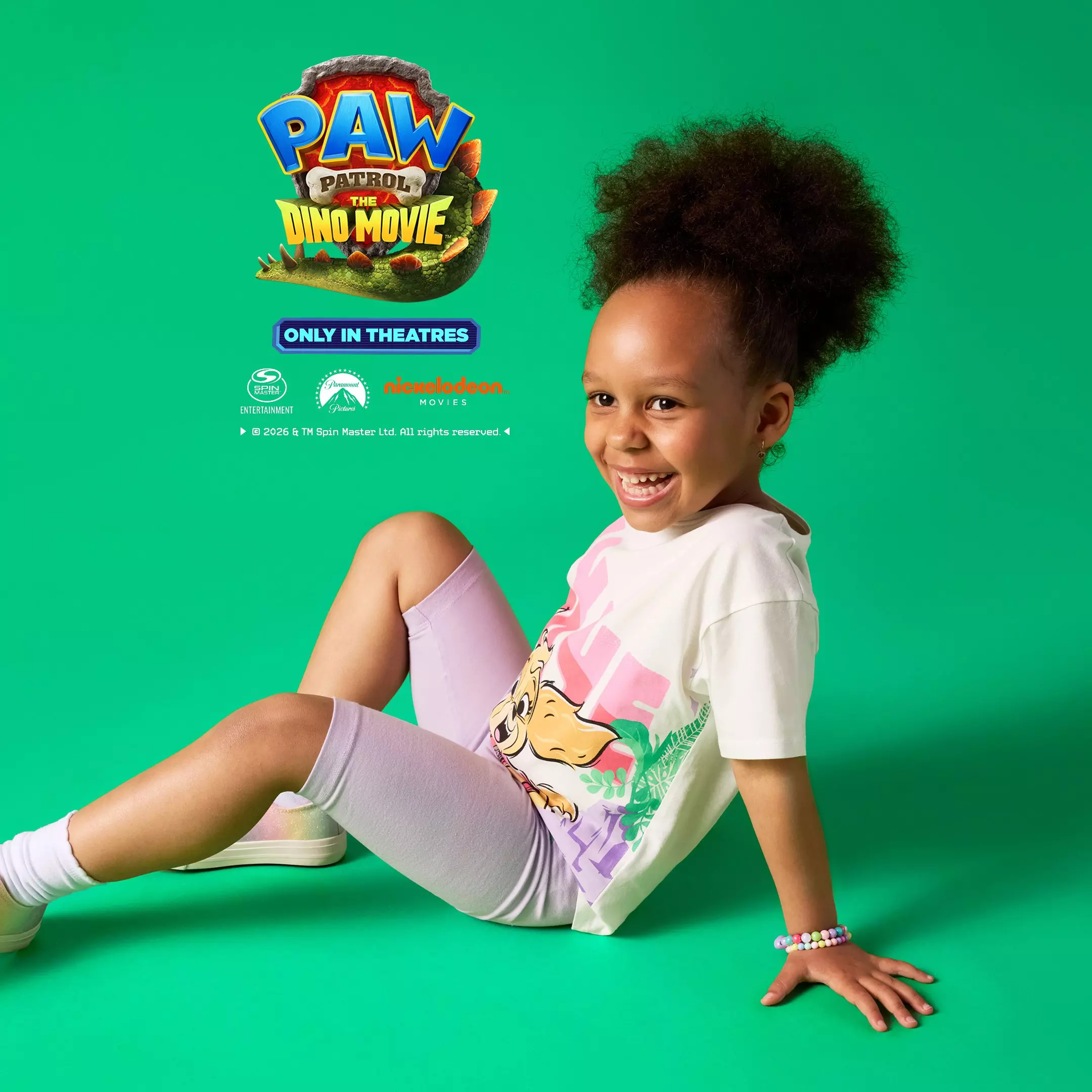 Dziecko w białej koszulce Pepco z grafiką PAW Patrol The Dino Movie i fioletowych legginsach.