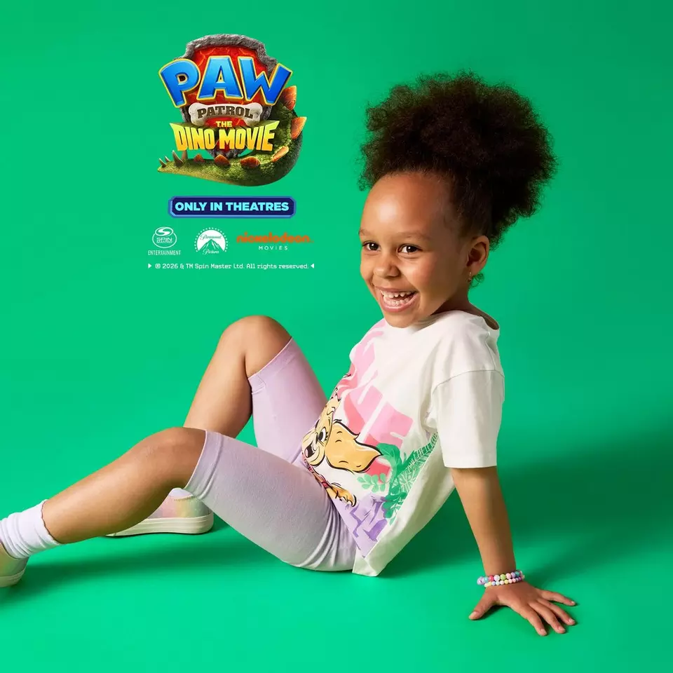 Dziecko w białej koszulce Pepco z grafiką PAW Patrol The Dino Movie i fioletowych legginsach.