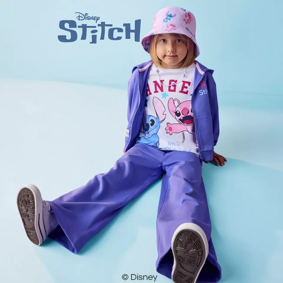 Copil purtând ținută sport Pepco Disney Stitch mov cu pălărie roz și adidași.