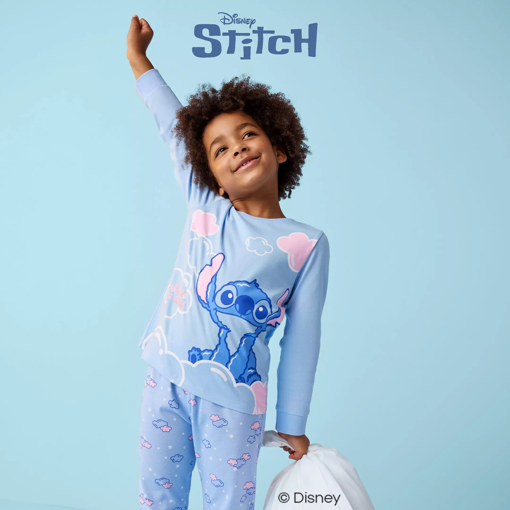 Child wearing Pepco Disney Stitch pyjamas with arm raised joyfully.