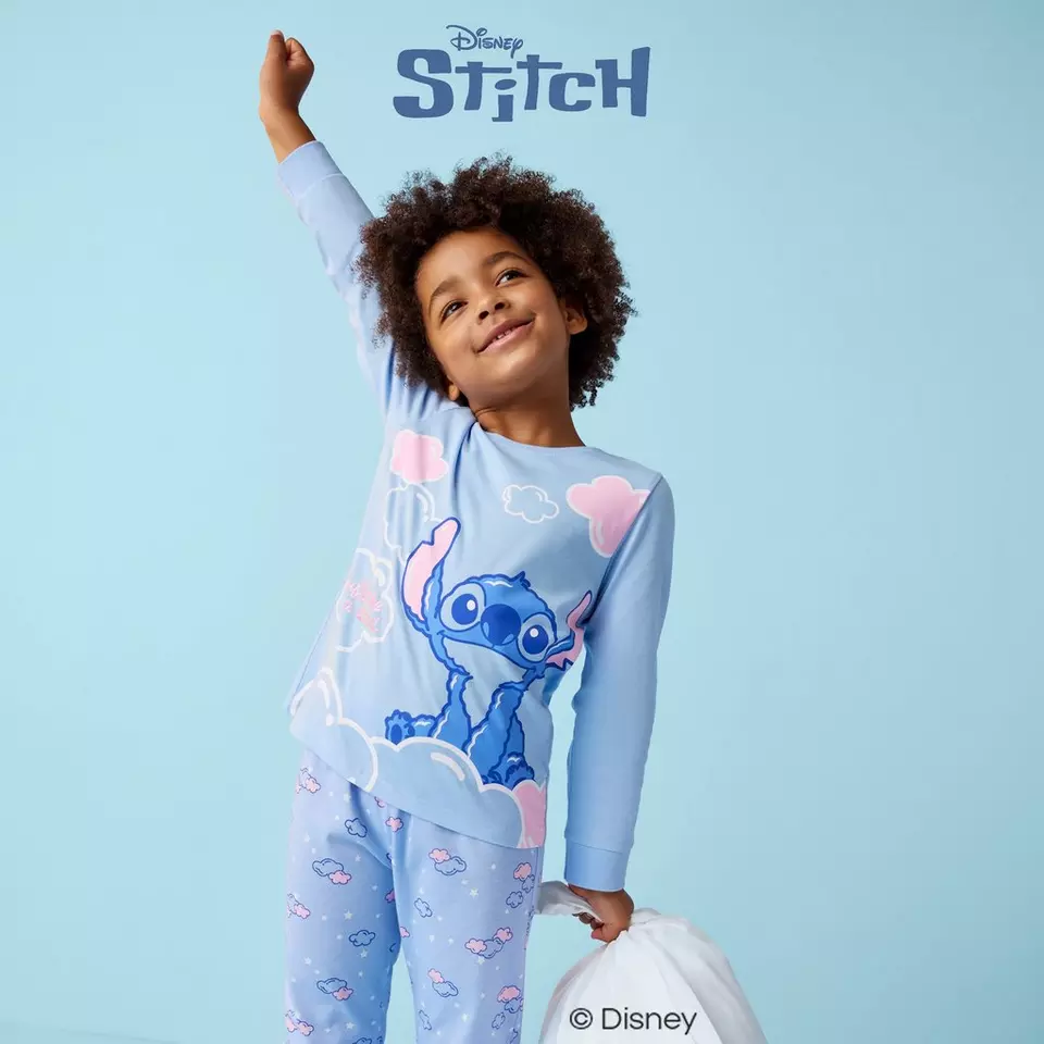 Child wearing Pepco Disney Stitch pyjamas with arm raised joyfully.