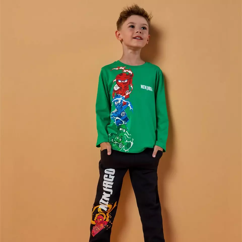Chlapec v zeleném tričku Pepco s motivem Ninjago a černých kalhotách s potiskem.