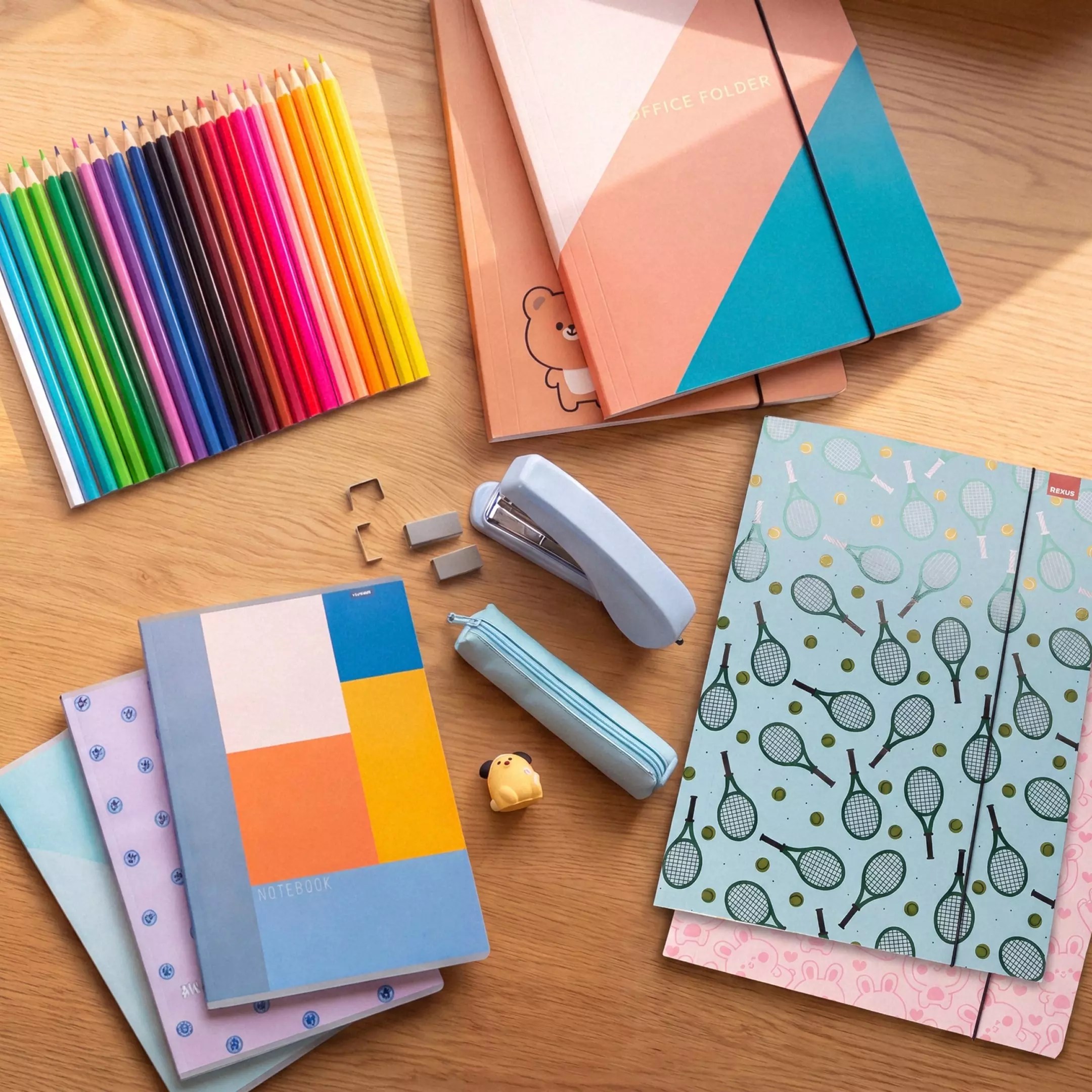 Pepco colourful stationery set including pencils, folders, notebooks, stapler and pencil case on wooden surface.