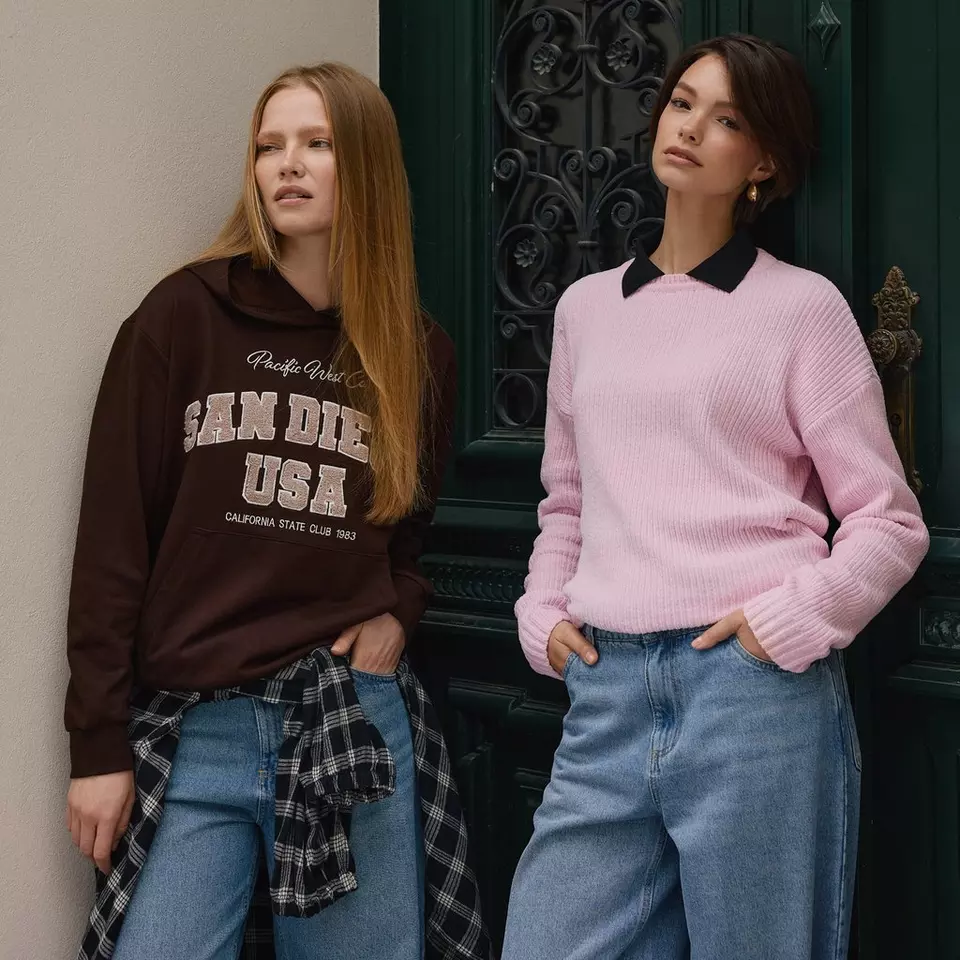 Two women modelling Pepco clothing: one in a brown San Diego hoodie, the other in a pink jumper with black collar.