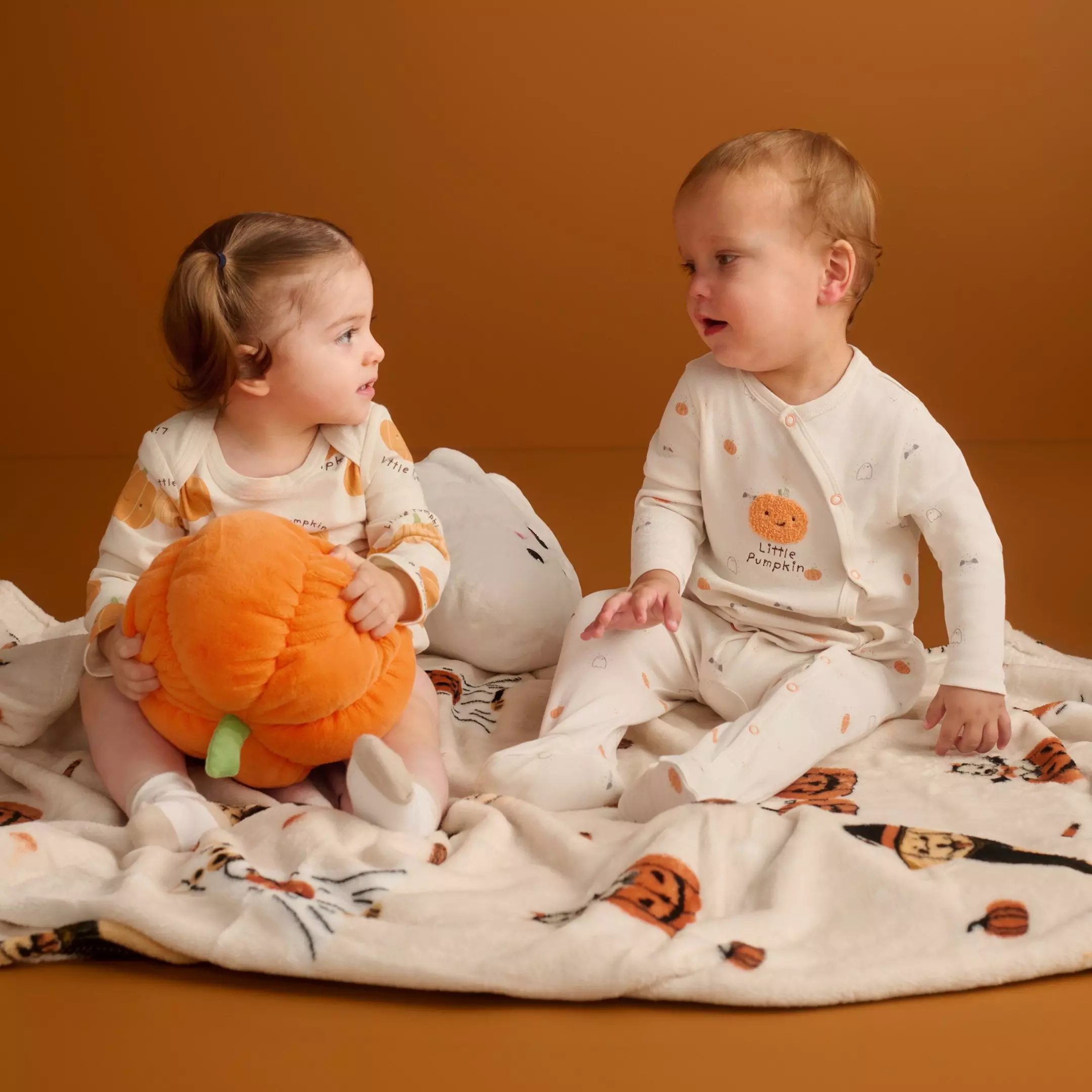 Due bambini Pepco indossano pigiami a tema Halloween con stampe Little Pumpkin e giocano con un peluche di zucca.