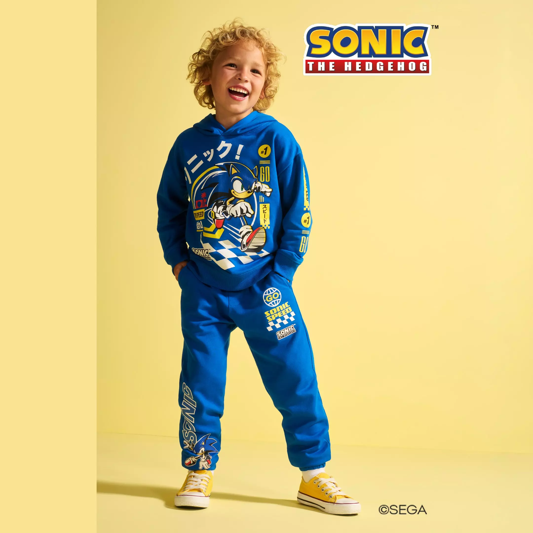Chlapec se směje v modré teplákovém soupravě Pepco s potiskem Sonic the Hedgehog.
