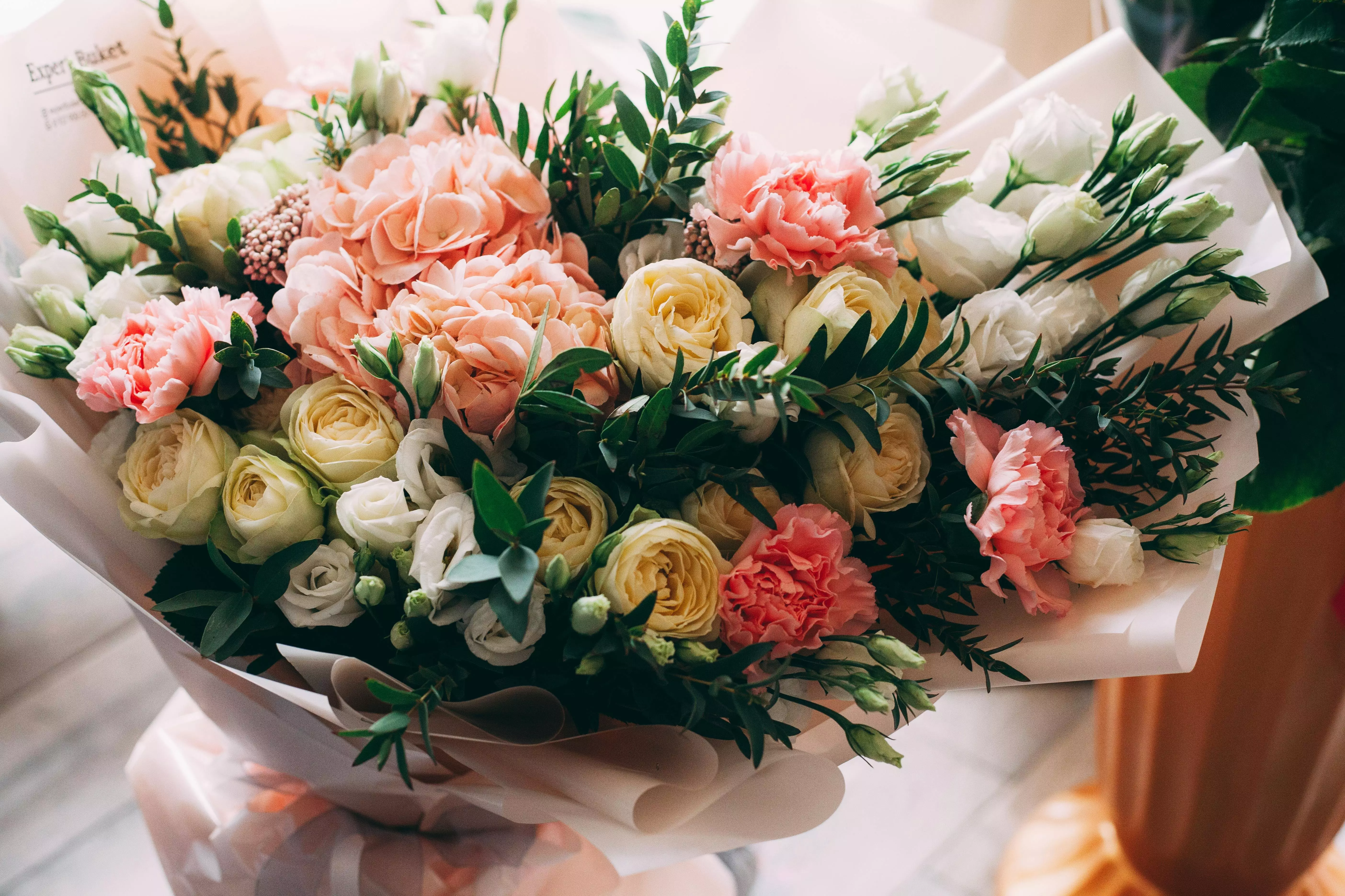 Bouquet Pepco con rose gialle, rosa e garofani avvolto in carta decorativa.