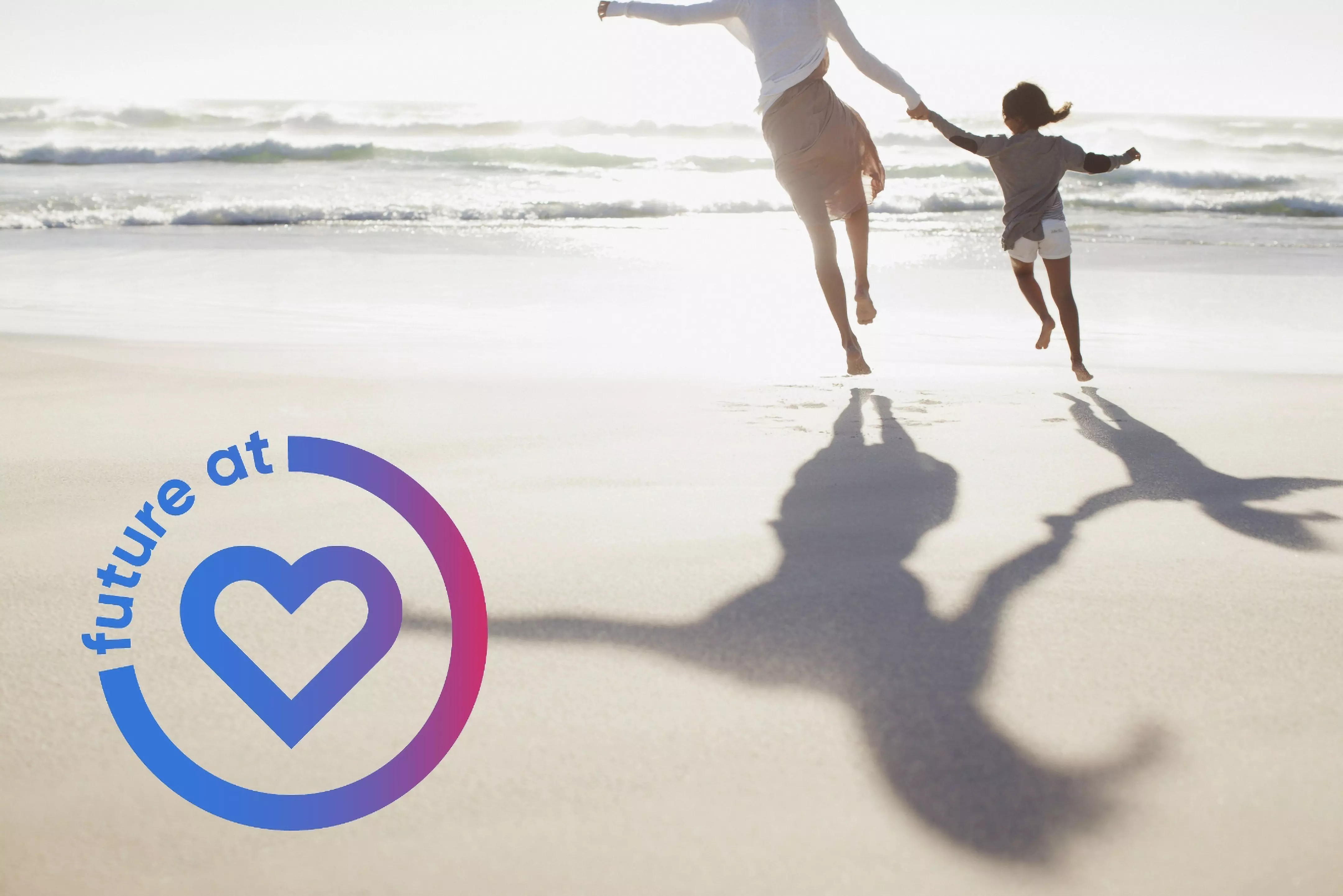 Dorosły i dziecko skaczą trzymając się za ręce na plaży z logo future at heart, promując wartości rodzinne Pepco.