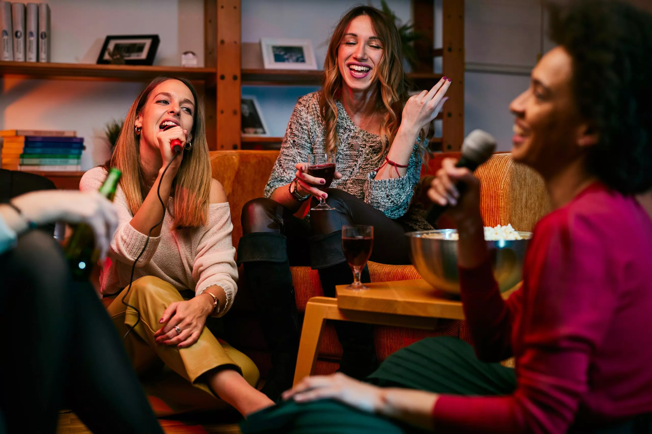 Gruppo di amiche Pepco che ridono e si divertono insieme durante una serata in casa con bevande.