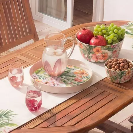Vajilla decorativa con motivos florales sobre mesa de madera con frutas y bebidas.