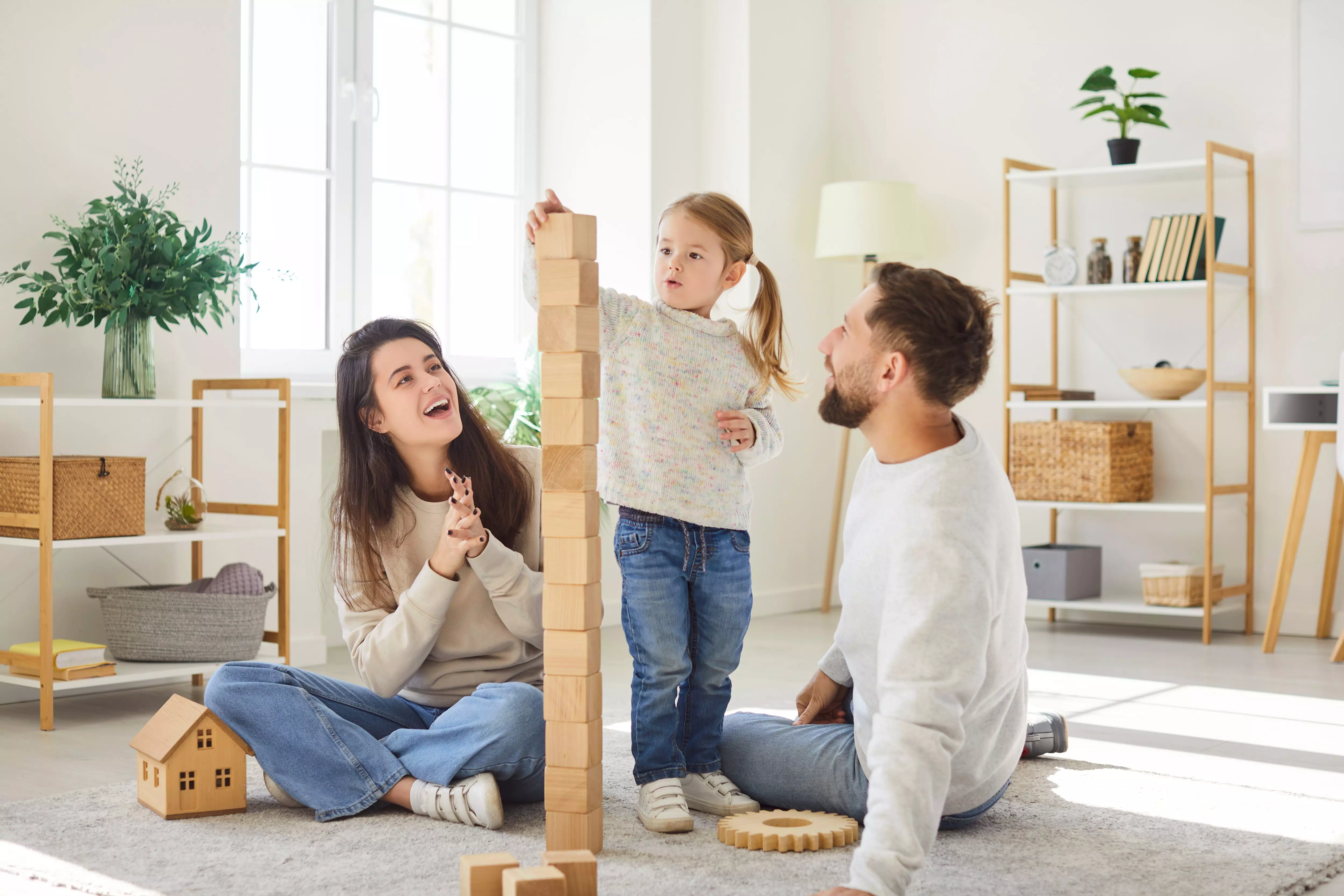 Pepco family playing with wooden building blocks together in a bright living room.