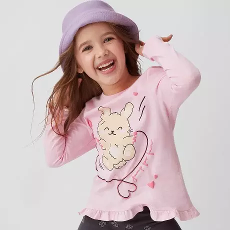 Dziewczynka w fioletowym kapeluszu nosi różową bluzkę Pepco z uroczym królikiem na sercu i falbanką na dole.