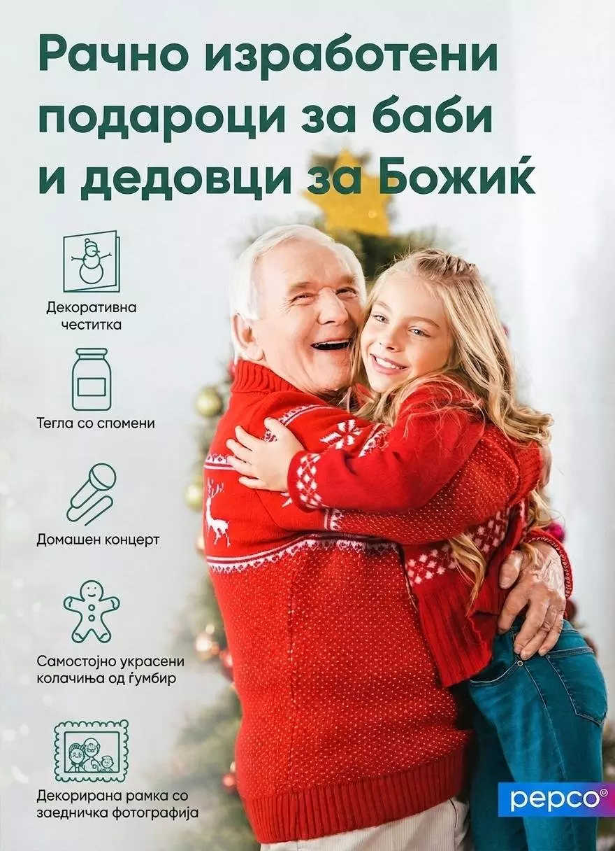 Pepco - дедо и внука во црвени божиќни џемпери се гушкаат пред украсена елка.