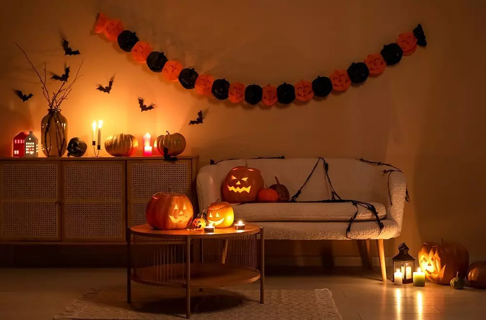Halloweenowa dekoracja Pepco z dyniami, girlandą z dyń, nietoperzami i świecami tworzącymi przytulną atmosferę.