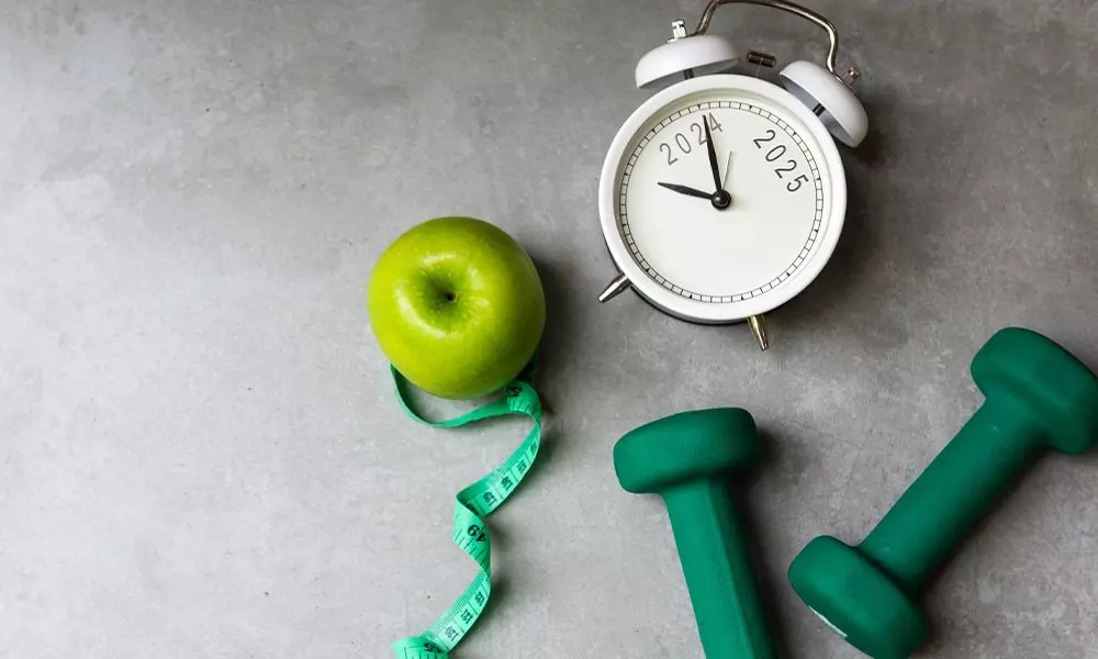 Białe urządzenie do pomiaru czasu Pepco z oznaczeniem 2024-2025, zielone jabłko z miarką i zielone hantle na szarym tle.