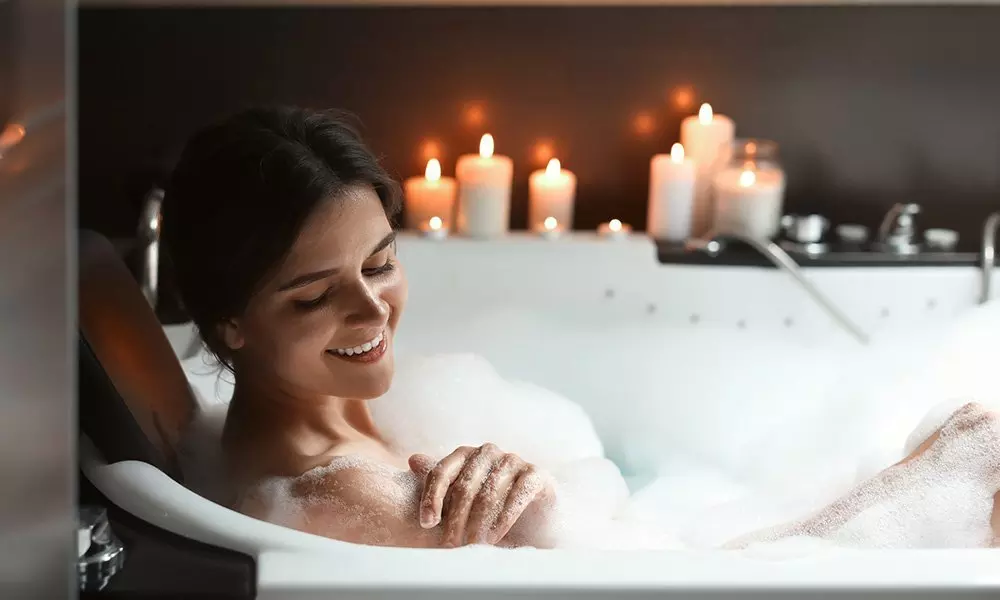 Osoba relaksująca się w pianie kąpielowej z produktami Pepco, otoczona zapalonymi świecami tworzącymi nastrojową atmosferę.