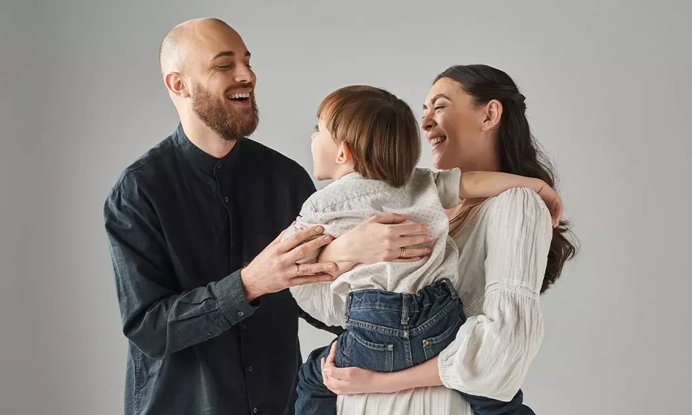 Pepco family portrait showing parents embracing their child, all smiling together in casual clothing.