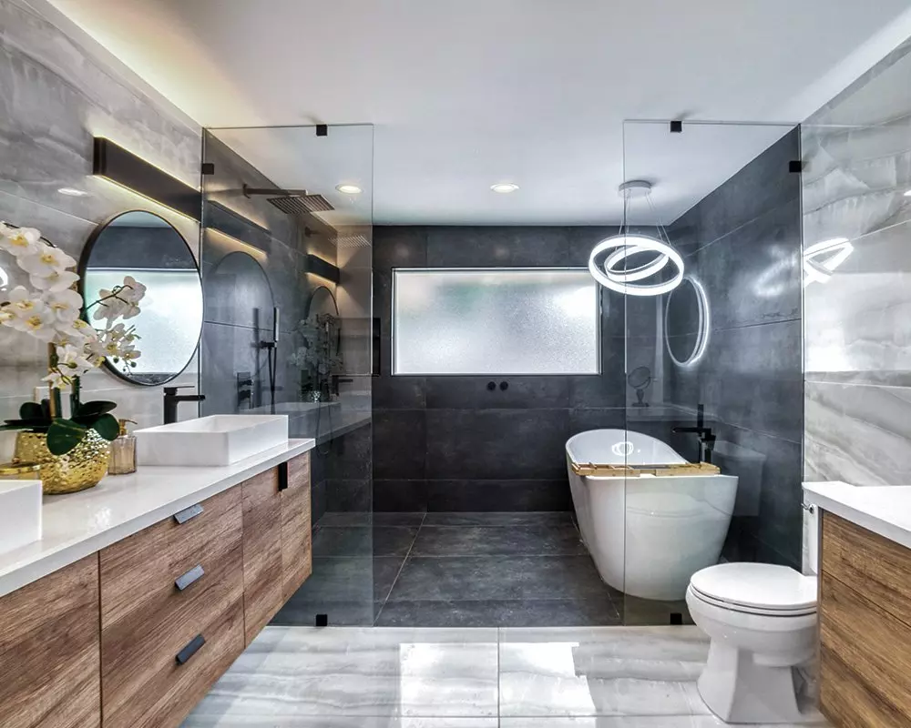 Nowoczesna łazienka z produktami Pepco, z wanną wolnostojącą, drewnianymi szafkami i okrągłym lustrem, oświetlona dekoracyjną lampą wiszącą.