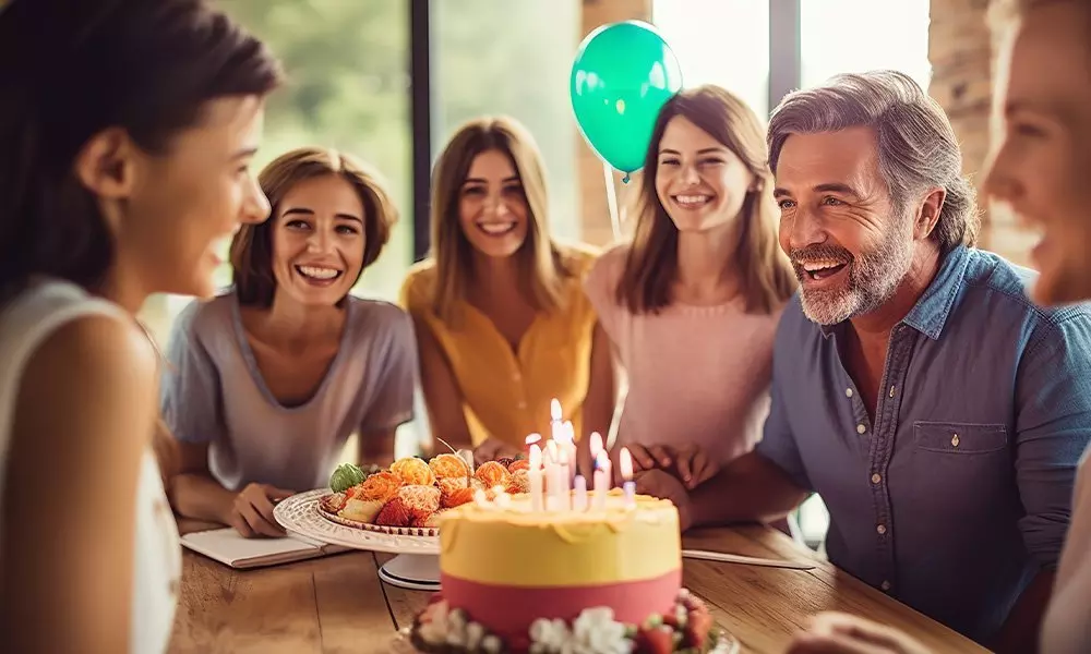 Pepco celebrates a birthday party with people gathered around a cake with lit candles and a green balloon.