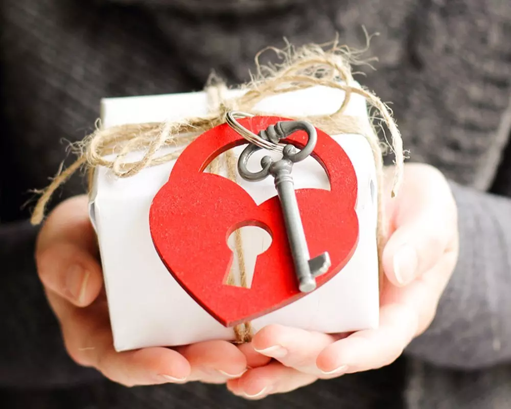Pepco Valentine's gift box with red heart-shaped lock and vintage key, tied with twine, held in outstretched hands.