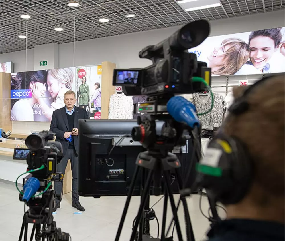Video cameras filming a press event at Pepco store with clothing displays and promotional signage visible in the background.