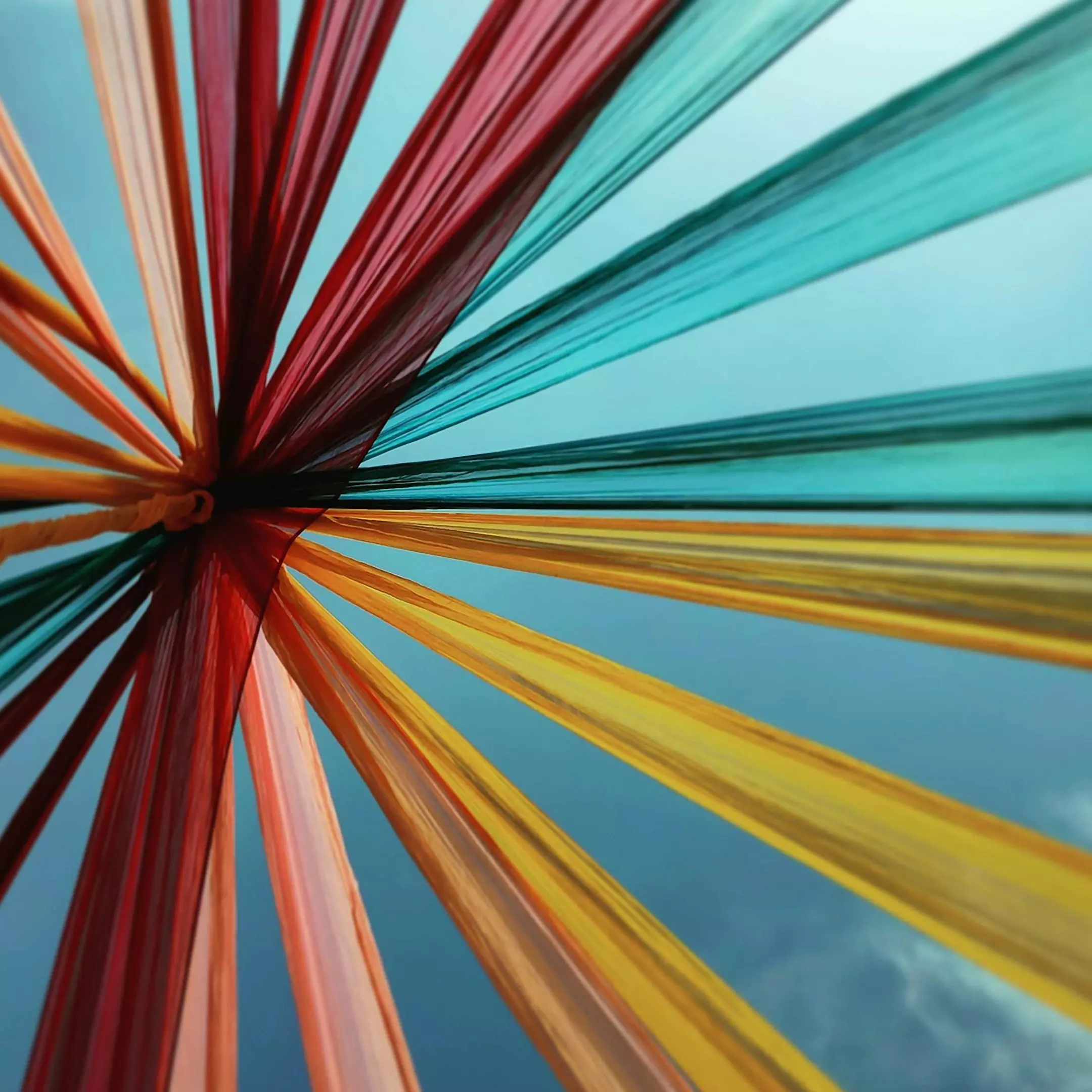 Colorful fan-like decoration from Pepco featuring red, yellow, turquoise and orange fabric strands radiating from center point.