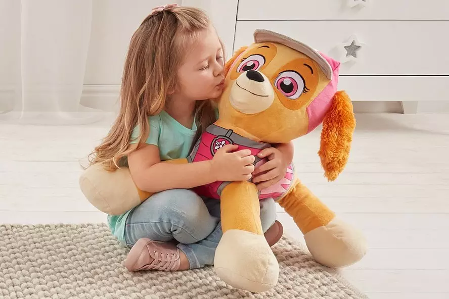 Dziecko przytula dużą pluszową maskotkę psa z Psiego Patrolu oferowaną w sklepie Pepco.