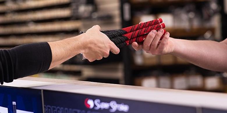 One store associate handing golf grips to another. 