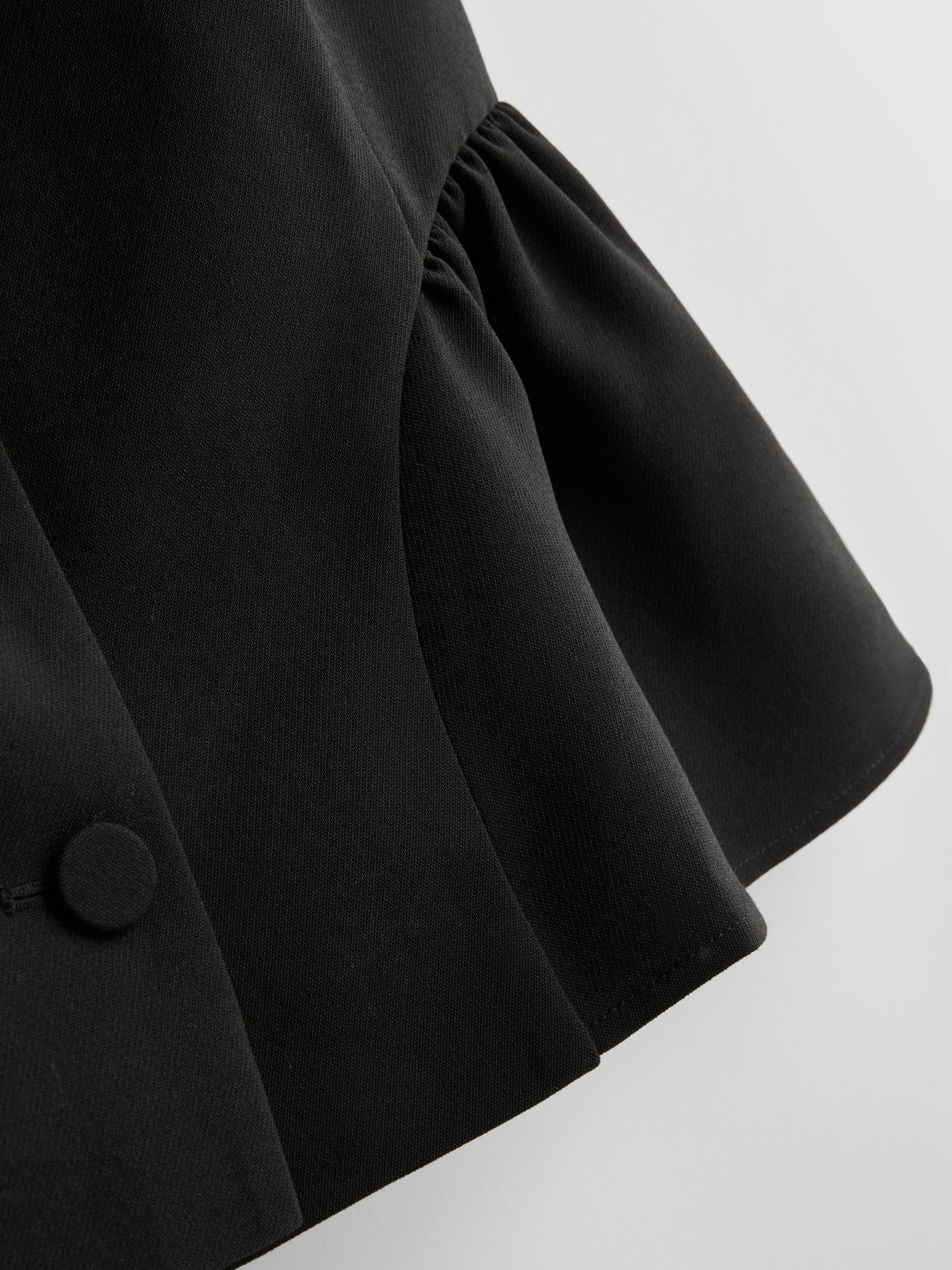 Vesta s peplum volánom a okrúhlym výstrihom