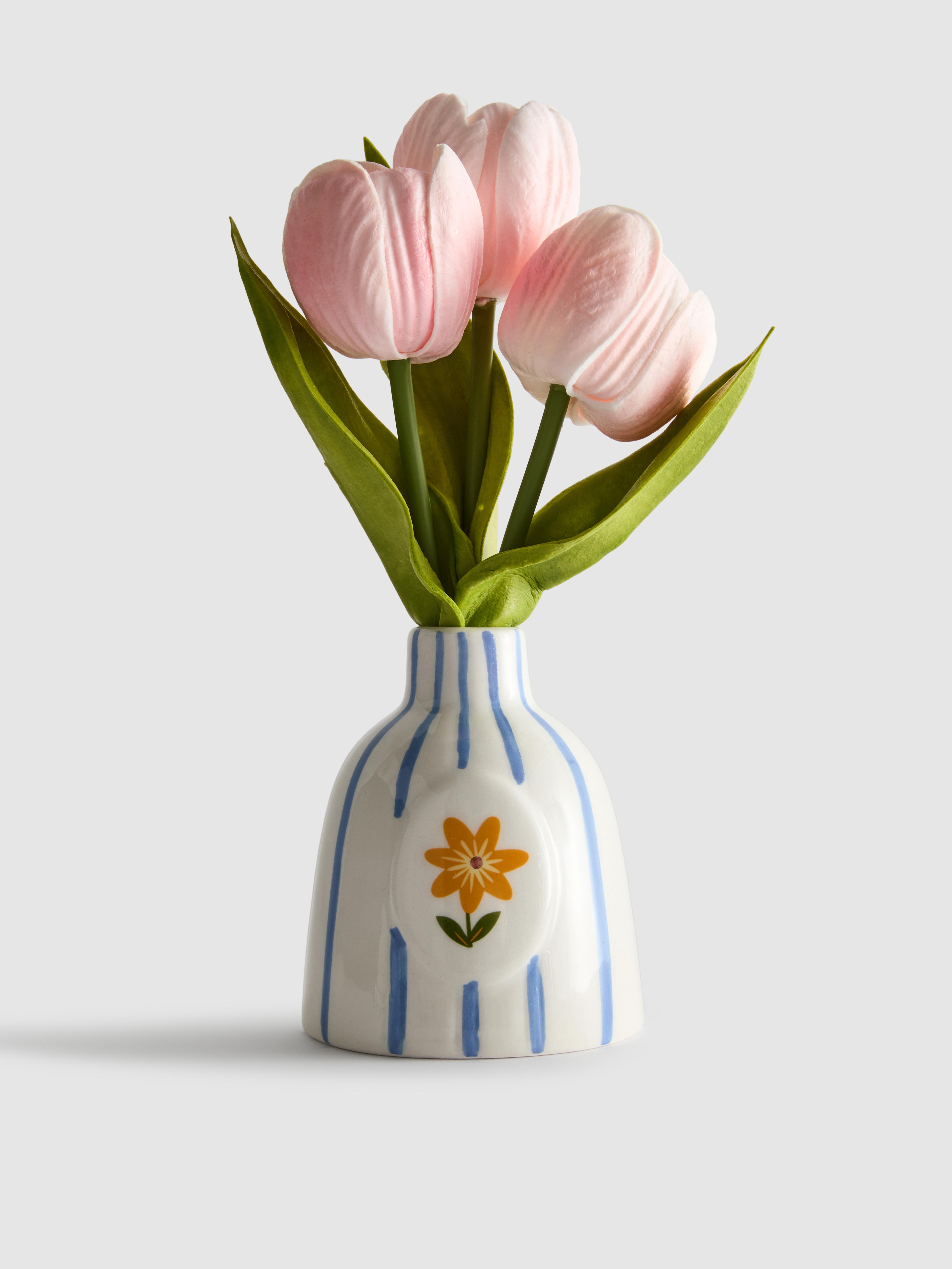 Tulipanes artificiales en jarrón a rayas