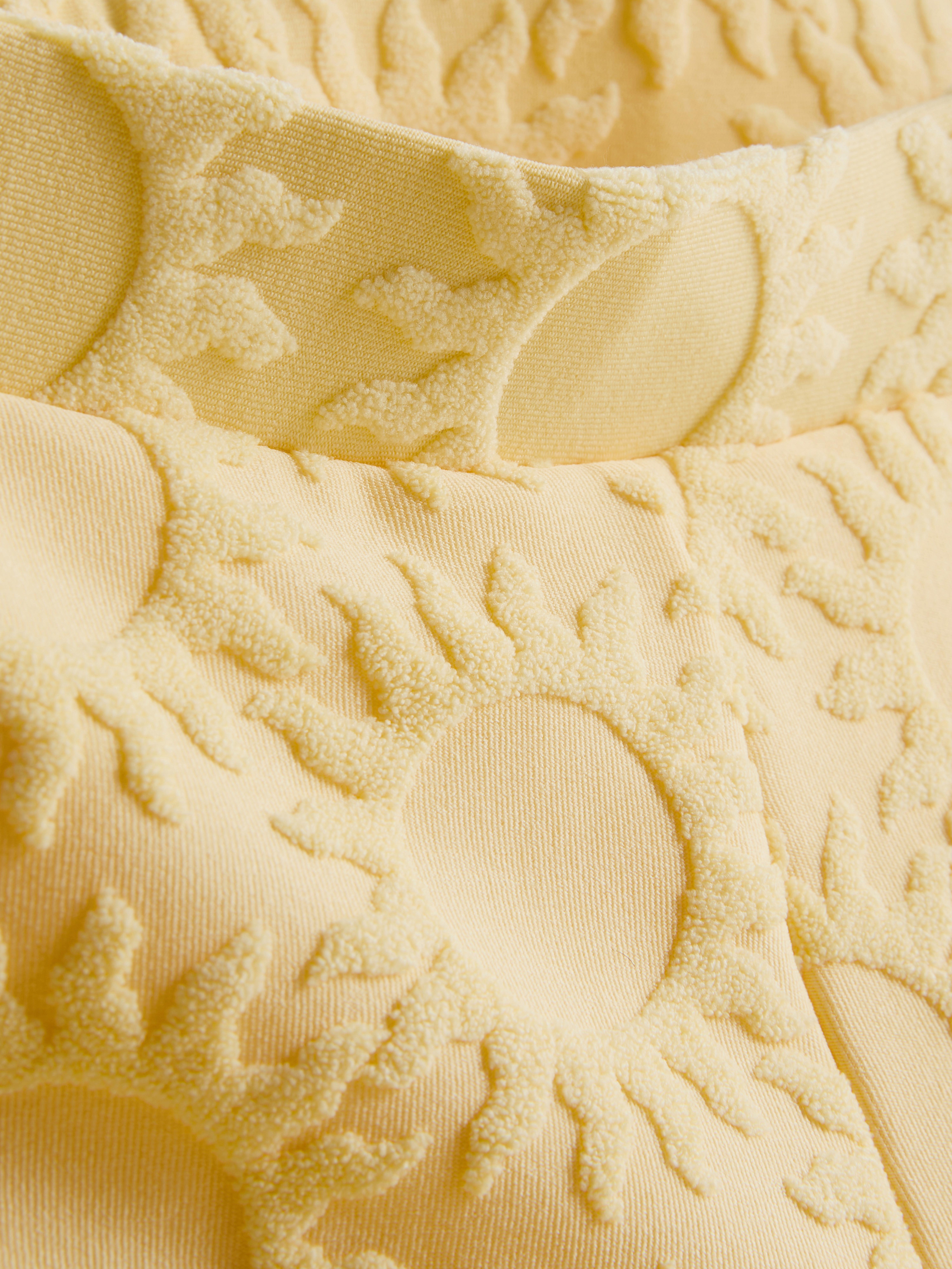 Strandshort met zonnemotief in reliëf