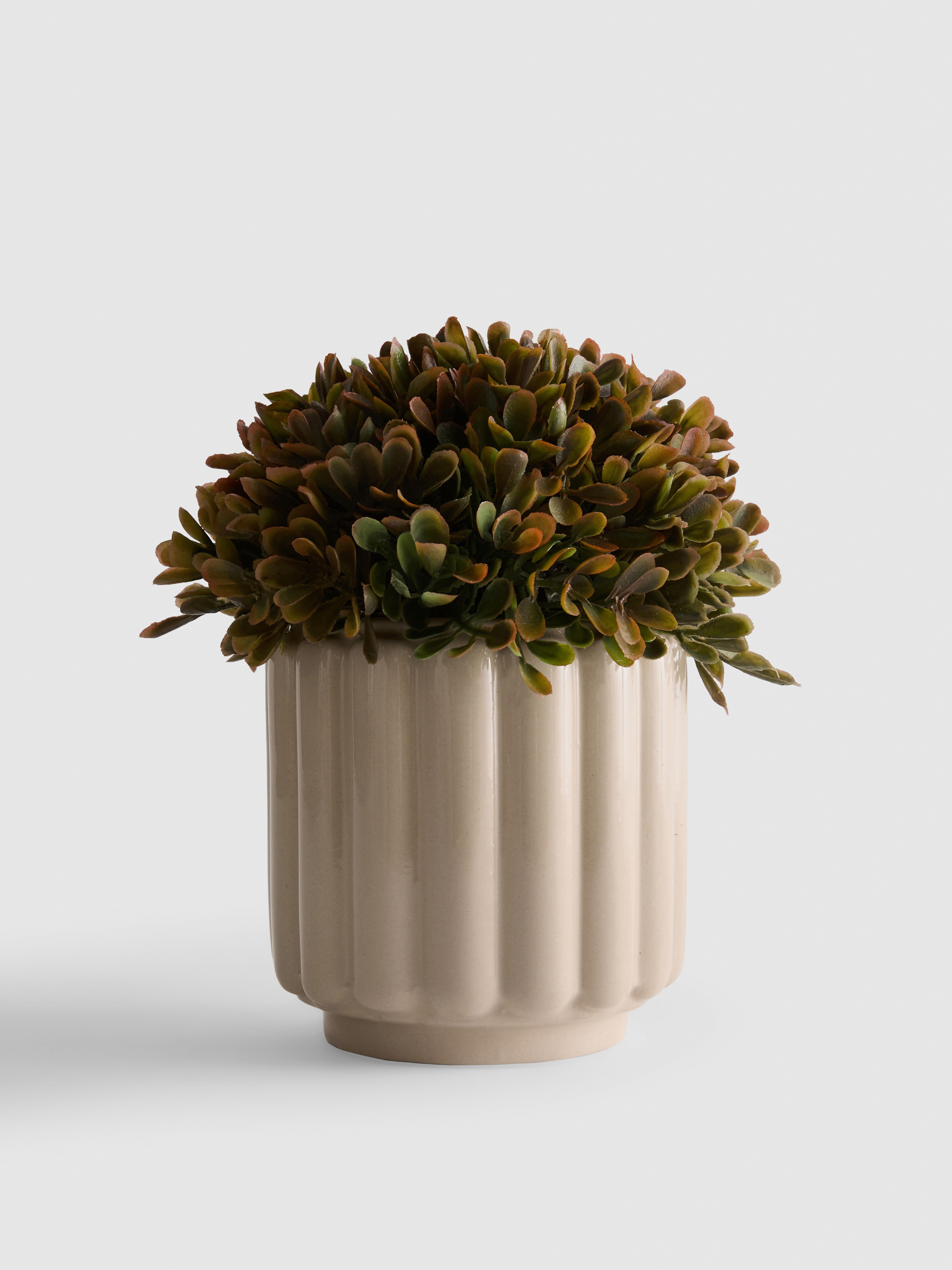 Plante artificielle dans un pot côtelé