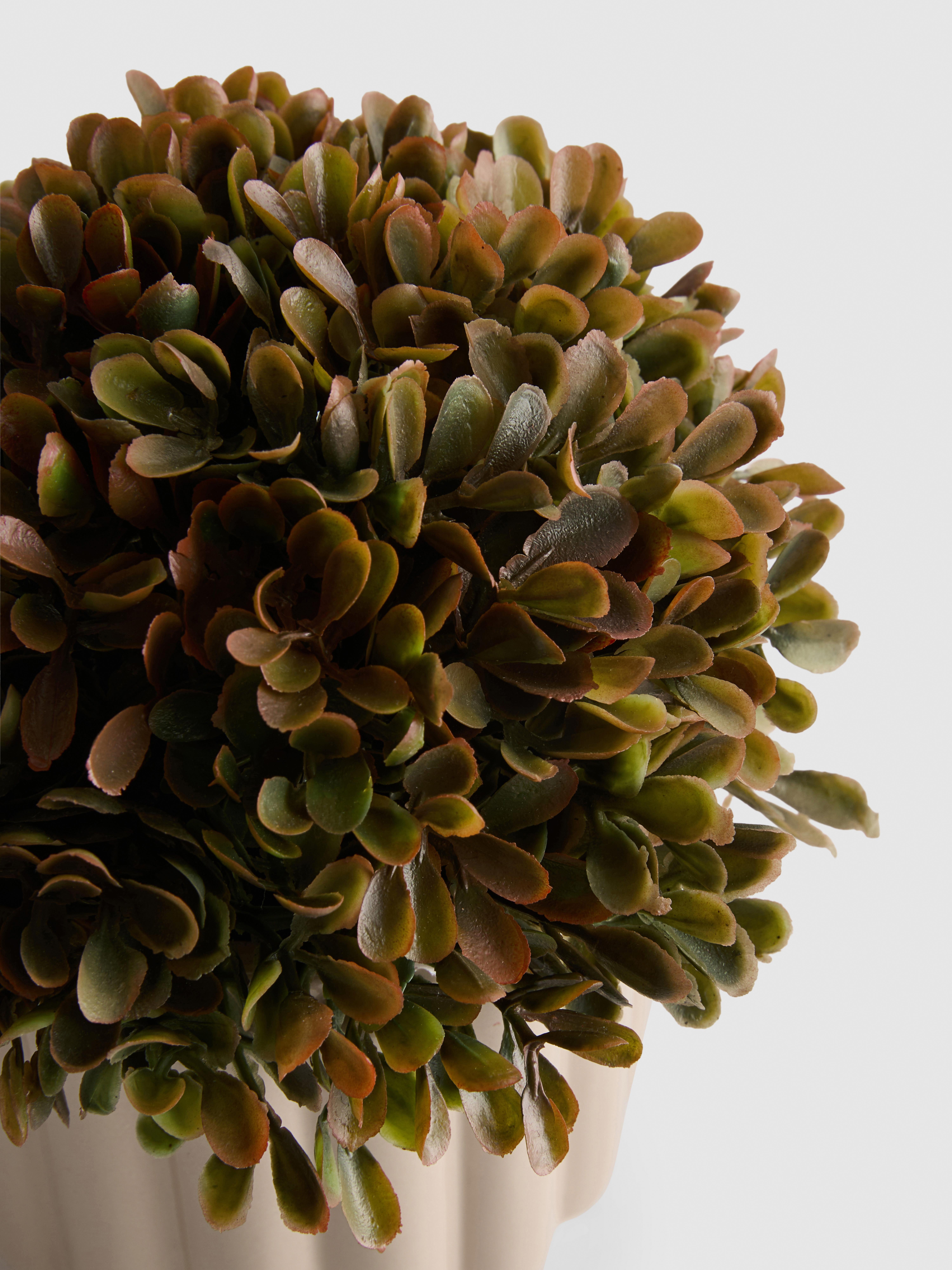 Plante artificielle dans un pot côtelé