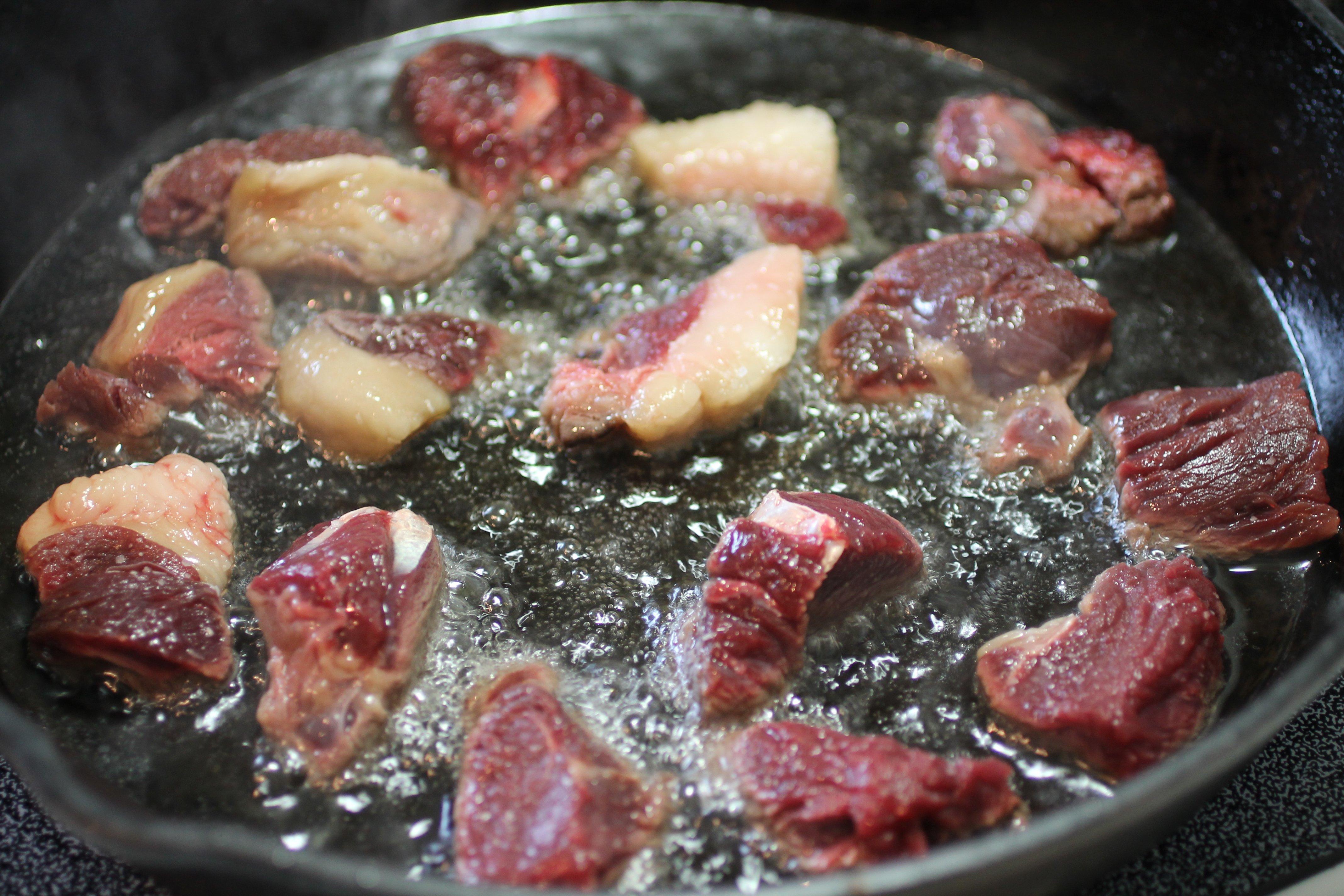 Brown the bear meat in hot oil for added flavor.