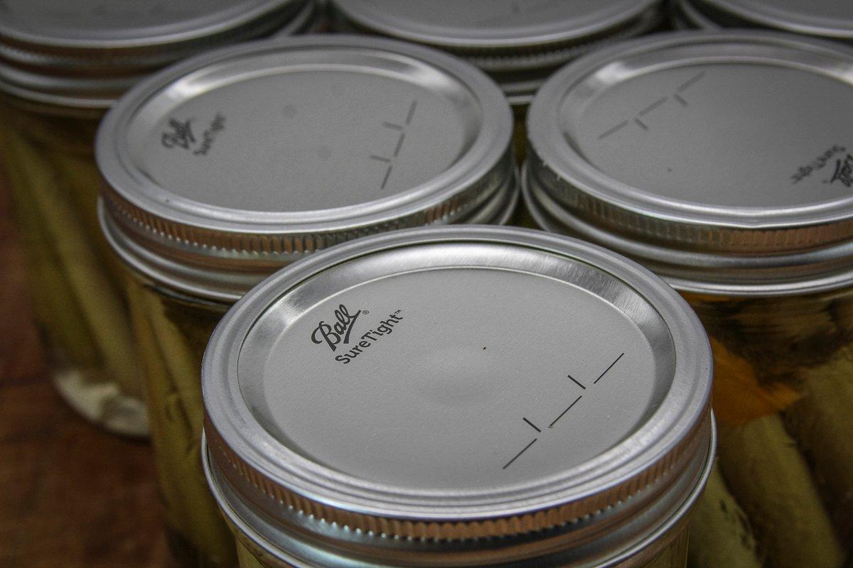 Move the jars to a towel lined counter and wait to hear an audible popping noise and see a sunken dimple to know the jars are sealed.