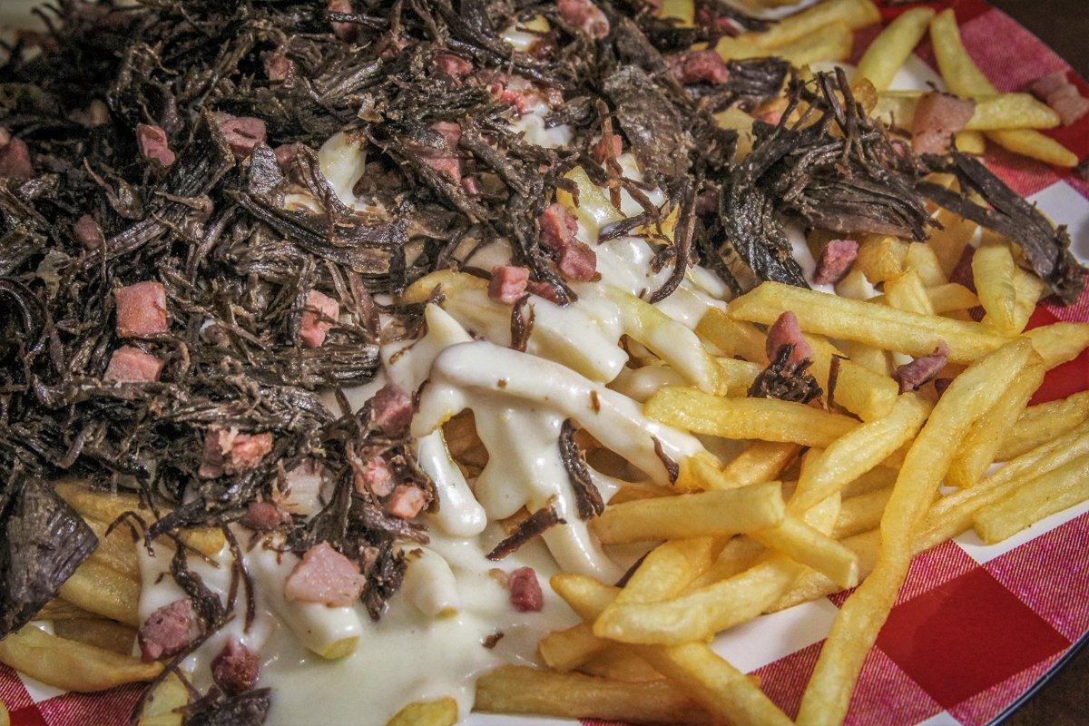 Top the crispy fries with the melted cheese sauce, then add the duck and country ham.