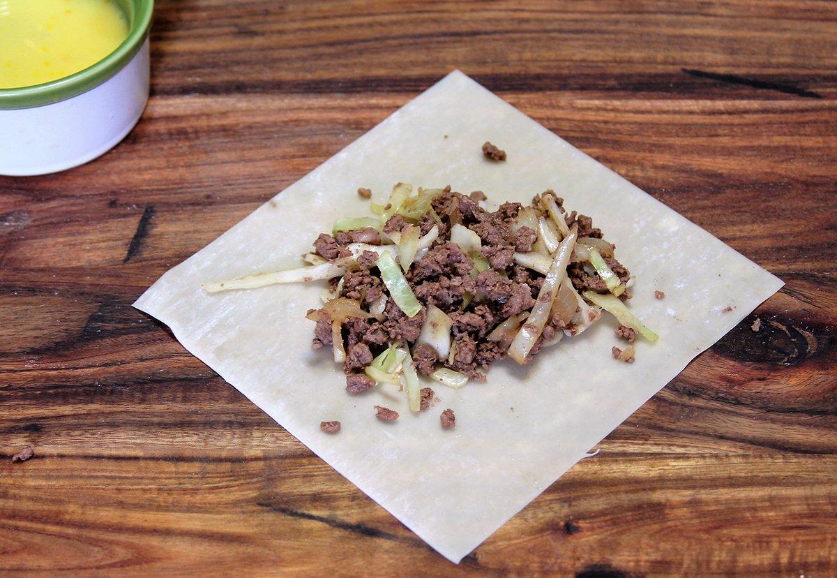 Spoon the filling mixture onto the center of the wonton wrapper to start the roll.