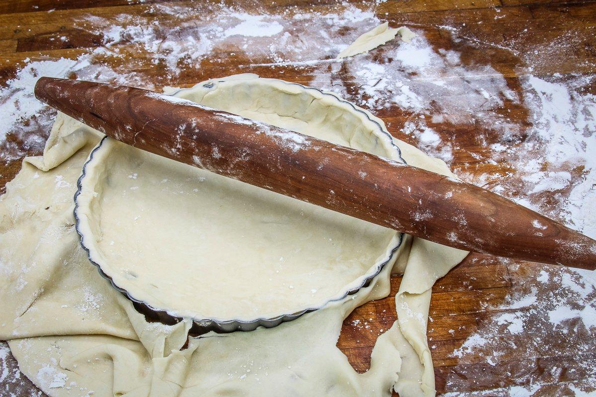 Roll the pie crust dough over the pan and use the roller to cut the edge.