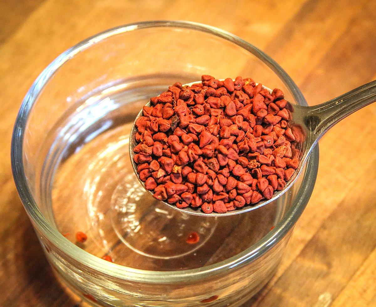 Soak the achiote seeds in warm water, then smash and strain. 