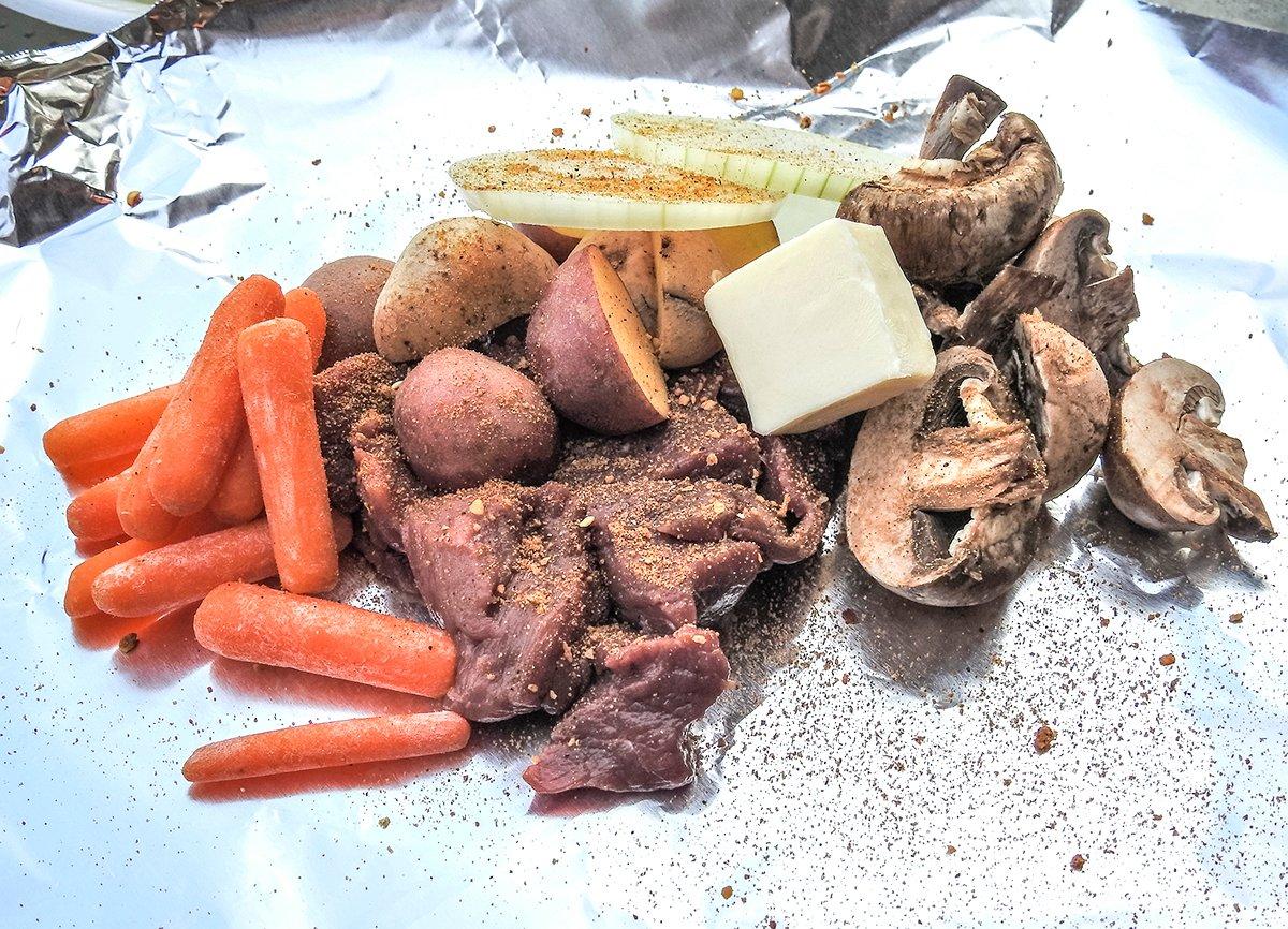 Add the venison, your favorite toppings, and a pat of butter. Season it up, pour in some liquid, seal it, then toss it in the coals.