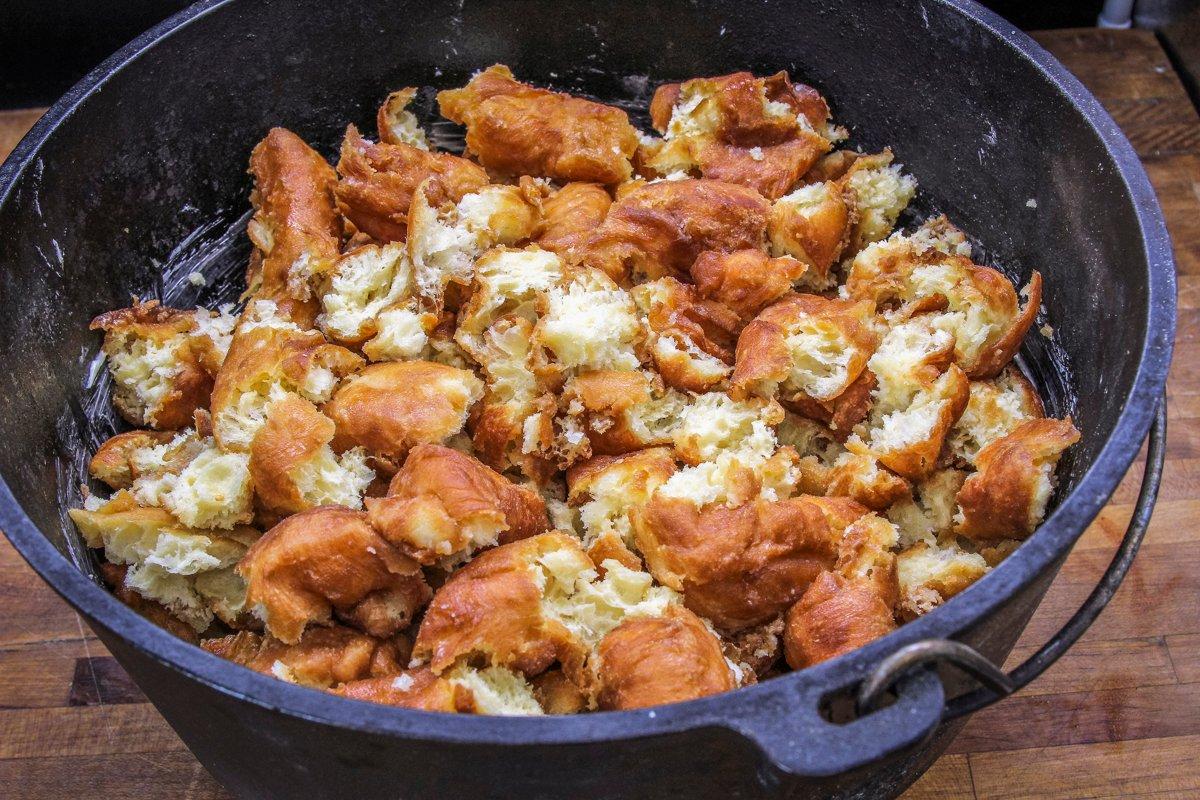 Tear the doughnuts into bits and add them to a buttered Dutch oven.