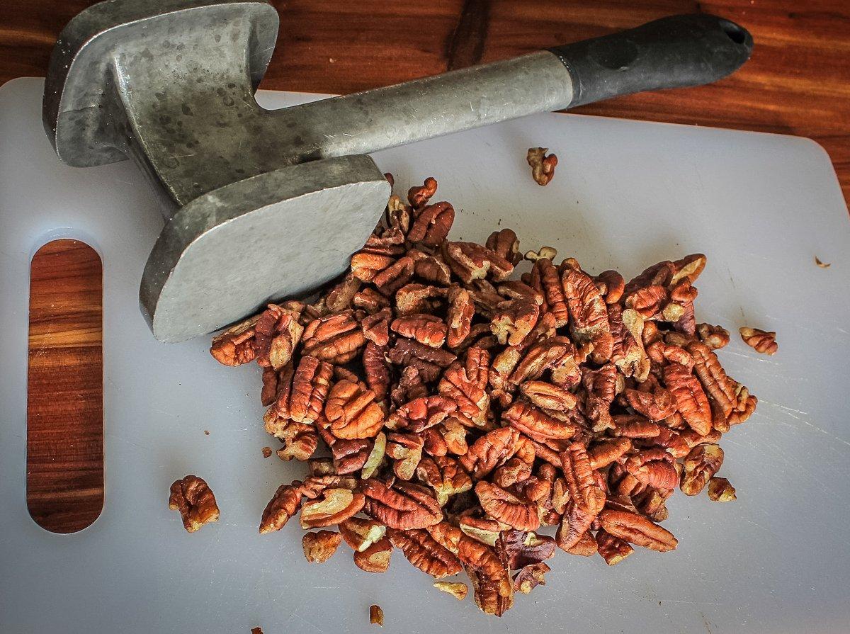 Roughly crush the pecans with a meat mallet.