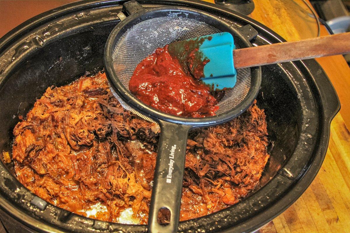 Push the ancho pepper pulp through a wire strainer into the cooked venison and pork. 