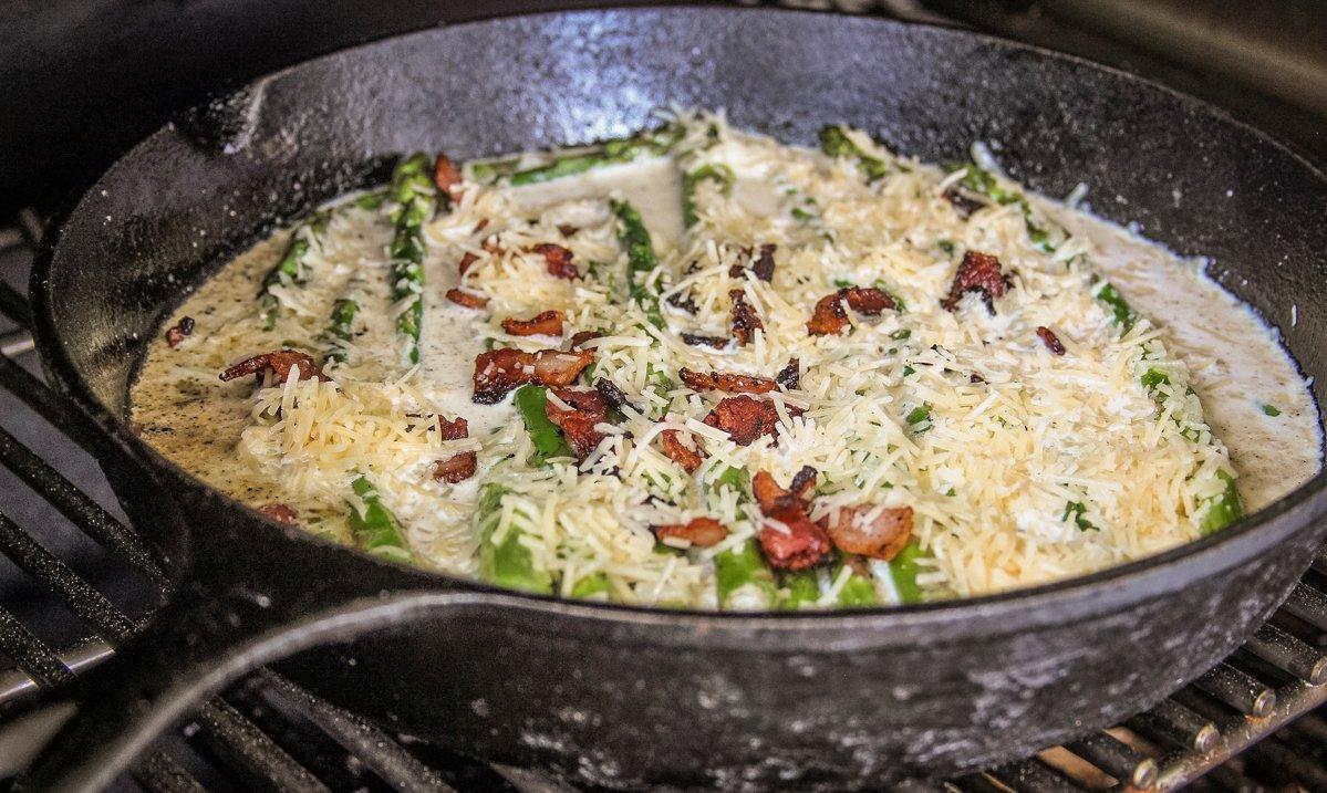 Add the cream, parmesan cheese, and bacon to the skillet and move it to your Traeger Grill.