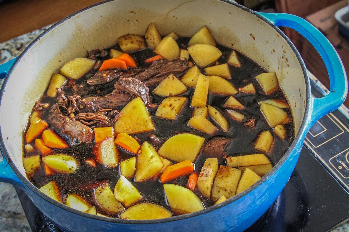 Add the onions, potatoes, peppers, and carrots and simmer until tender.
