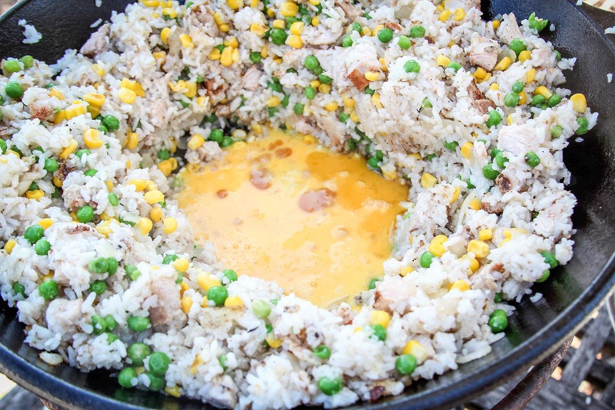 Pull the rice to the sides of the wok then add the beaten egg to the center, stirring it in as the egg cooks.