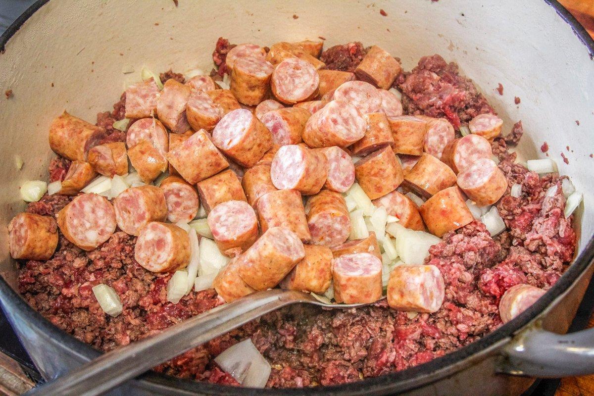Brown the ground venison, sausage and onion in a large pot.