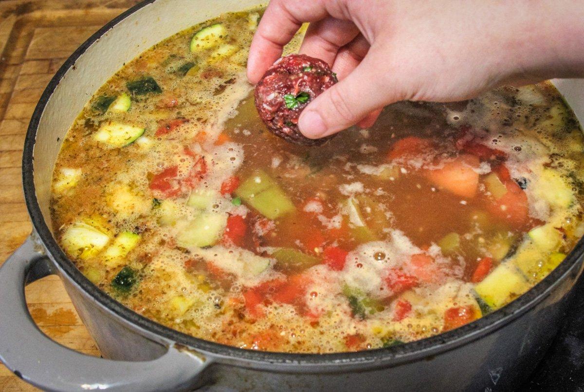 Drop the meatballs one at a time into the simmering soup stock.